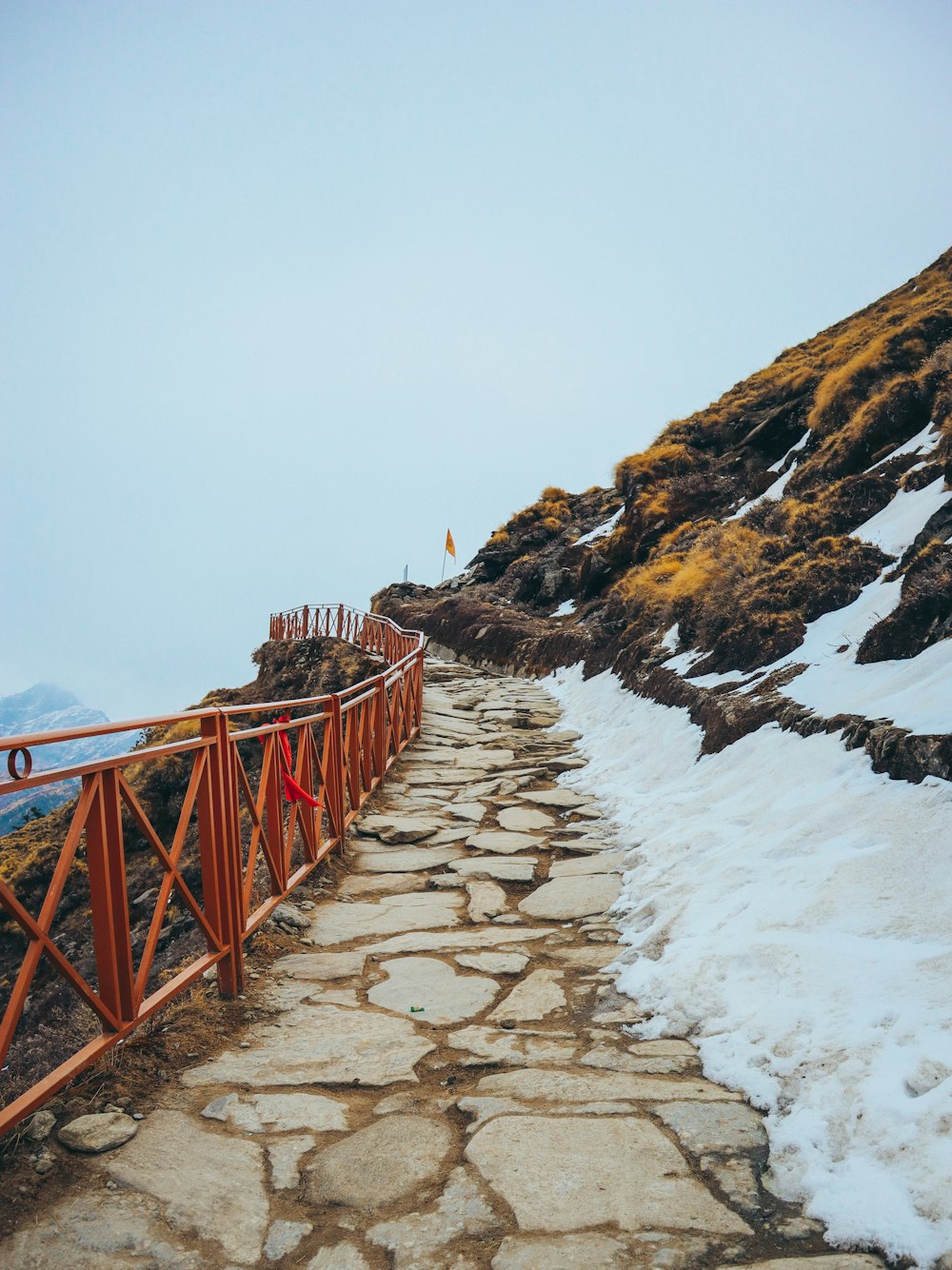 a stone path leading up a mountain covered in snow