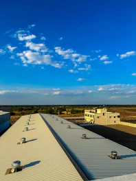 Technician inspecting a large commercial rooftop under clear skies.