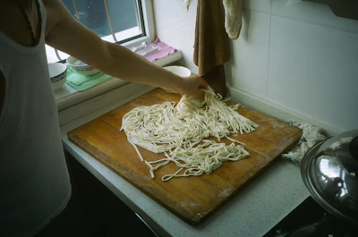 Close-up of steaming biangbiang noodles being hand-pulled in the kitchen.