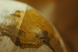 A close-up view of a vintage globe focusing on the South American continent, with countries like Colombia and surrounding areas partially visible. The map details are slightly faded, adding to the antique aesthetic.