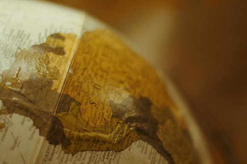 A close-up view of a vintage globe focusing on the South American continent, with countries like Colombia and surrounding areas partially visible. The map details are slightly faded, adding to the antique aesthetic.