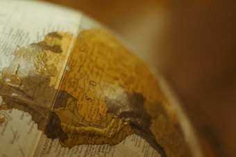 A close-up view of a vintage globe focusing on the South American continent, with countries like Colombia and surrounding areas partially visible. The map details are slightly faded, adding to the antique aesthetic.