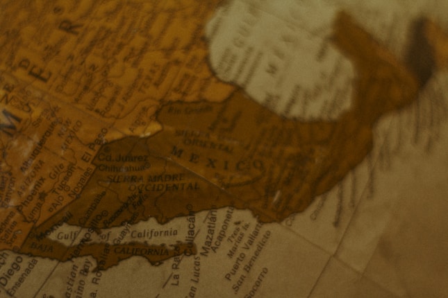 A close-up of a vintage-style globe showing parts of Mexico and the southwestern United States. The focus is on various city names and geographical features like the Sierra Madre Occidental. The overall look is warm and sepia-toned, suggesting an antiquated or nostalgic style.