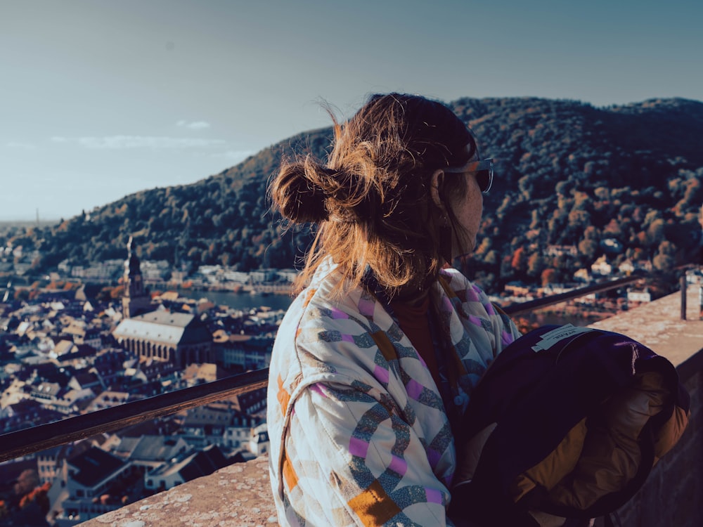 a woman with a backpack looks out over a city