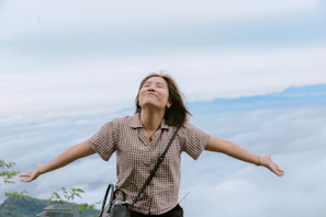 A peaceful moment outdoors, a woman enjoying fresh air with open arms and a smile.