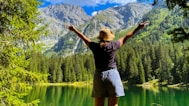 a woman standing in front of a mountain lake