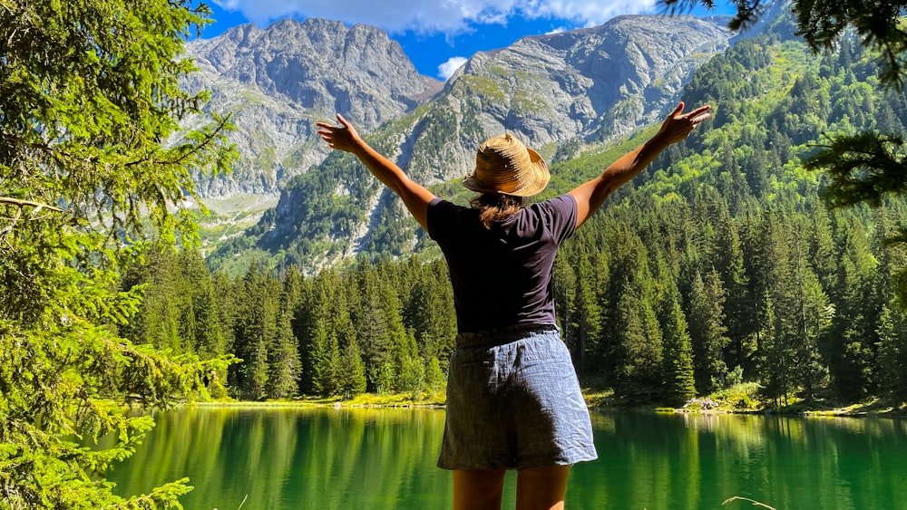 a woman standing in front of a mountain lake