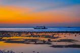 Sunset over a serene beach with traditional dhow boats in Zanzibar.