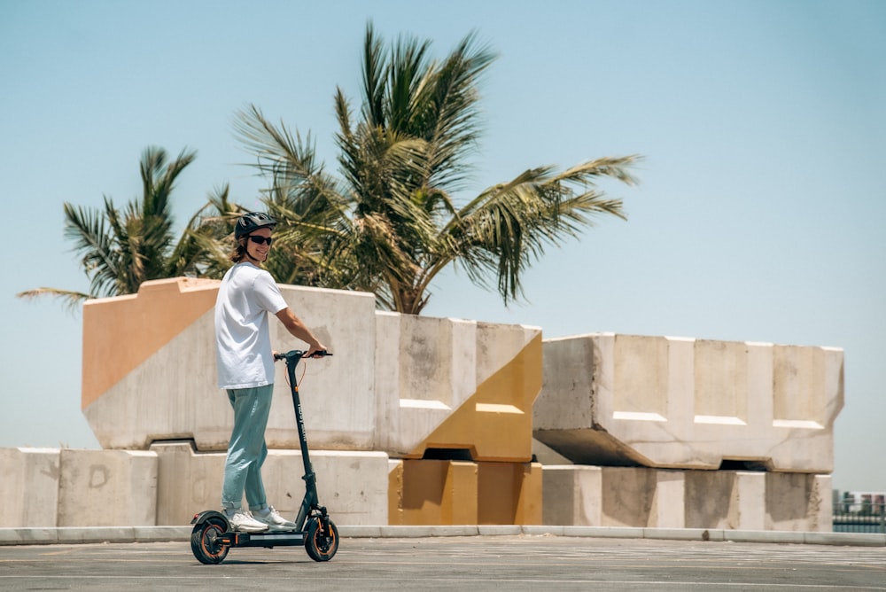 a man riding a scooter next to a palm tree