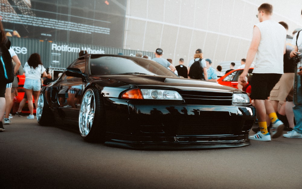 a black car parked in front of a crowd of people