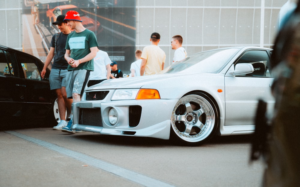 a group of people standing around a white car