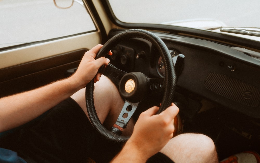 a man driving a car with a steering wheel