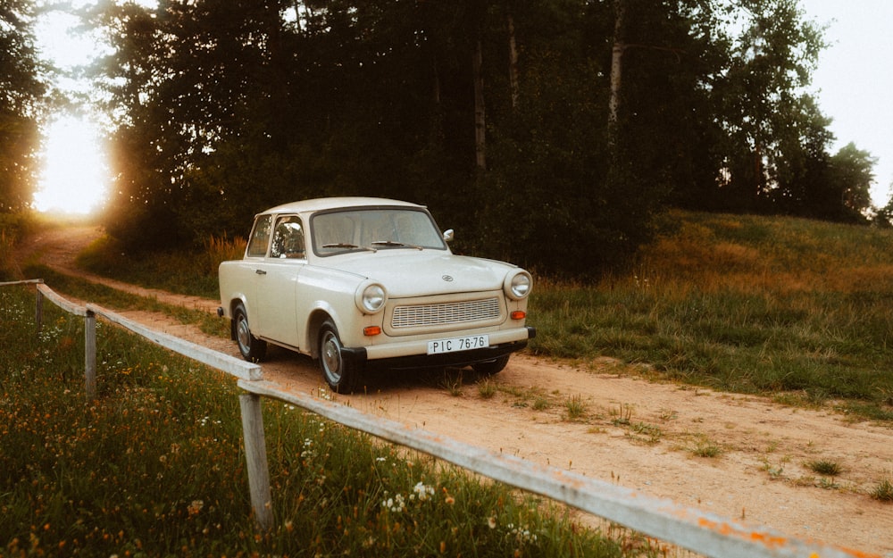 an old car is parked on a dirt road