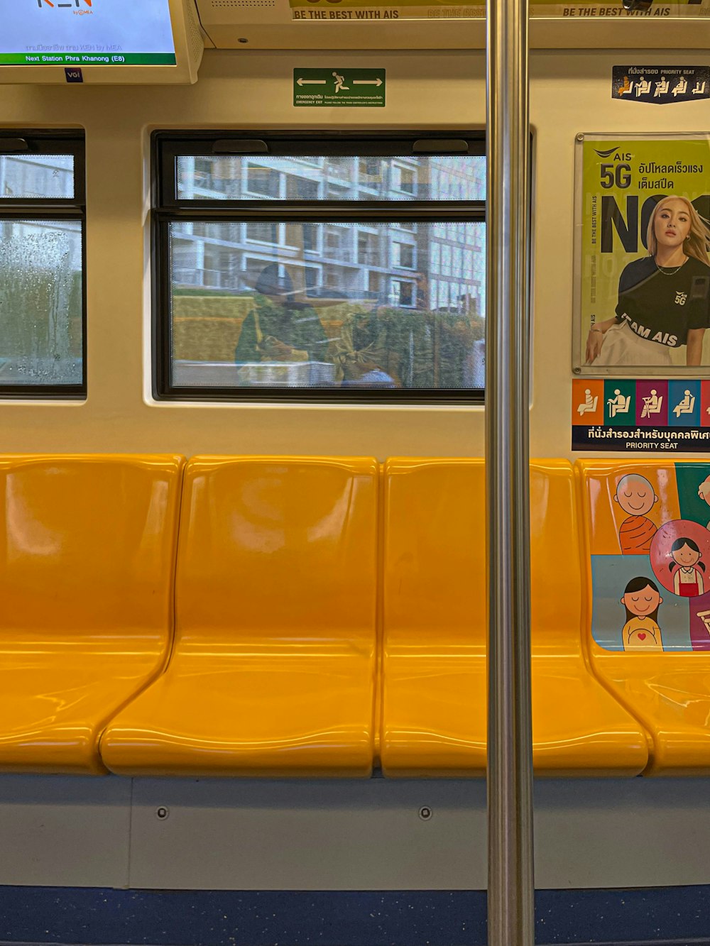 a subway car with yellow seats and posters on the wall