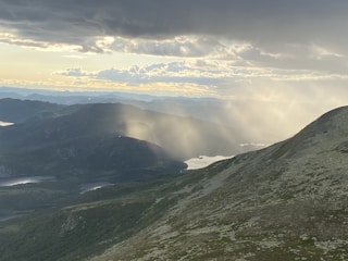Sunshine streaming over rolling mountains surrounded by lush greenery.