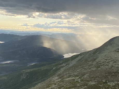 Sunshine streaming over rolling mountains surrounded by lush greenery.