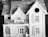 A detailed scale model of a house, featuring intricate architectural elements. The miniature structure includes a gabled roof, window shutters, and a small balcony or porch area. The craftsmanship suggests a classic, possibly Victorian style.
