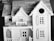 A detailed scale model of a house, featuring intricate architectural elements. The miniature structure includes a gabled roof, window shutters, and a small balcony or porch area. The craftsmanship suggests a classic, possibly Victorian style.