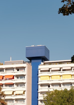 After photo showing the same residential building with fresh blue paint and modern finishes.