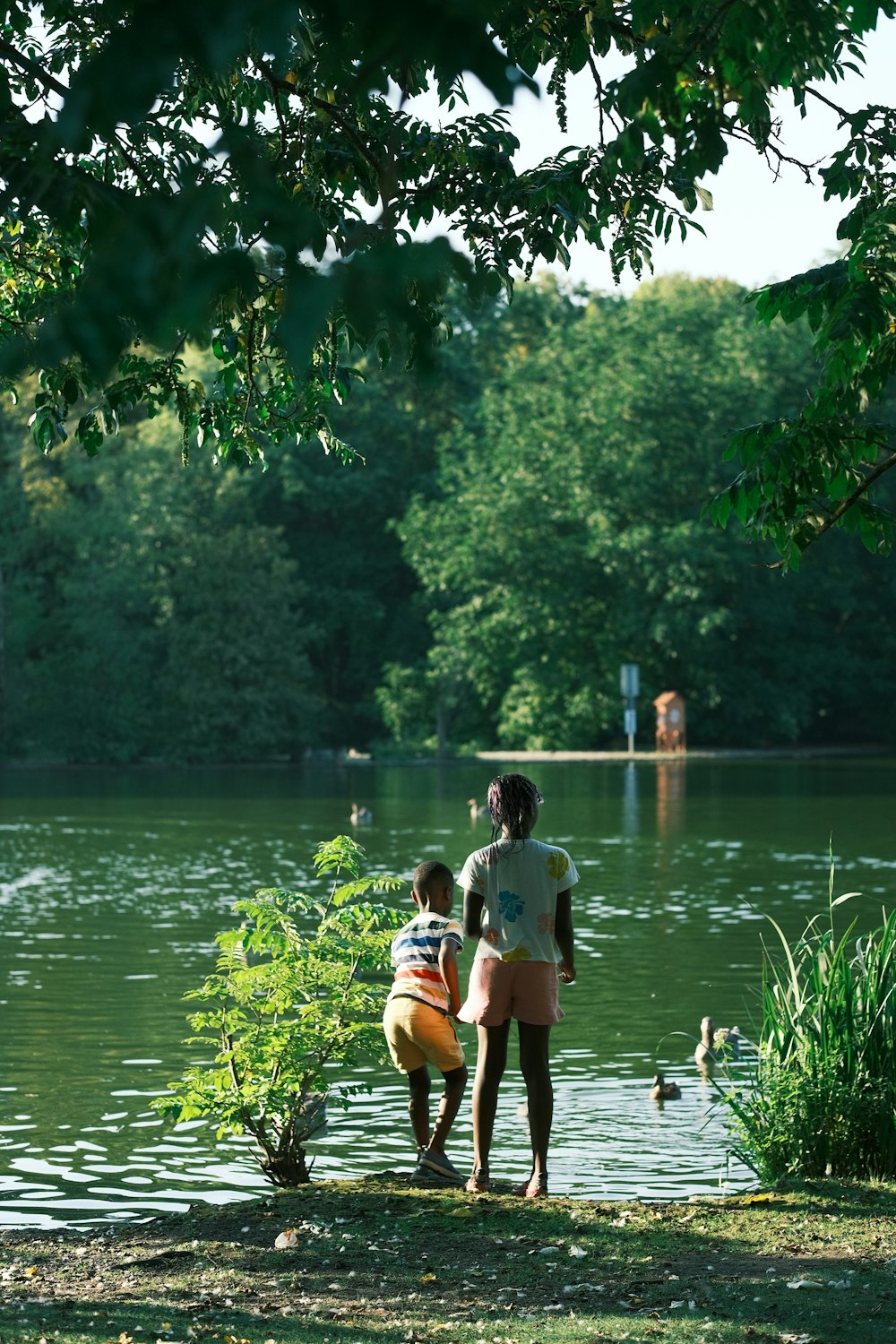 a woman and a child standing by a lake