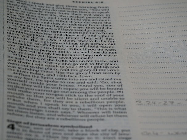 A close-up view of a page from the Bible with text focusing on a specific passage. The right side of the image features a notebook with lined pages for note-taking.