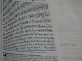 A close-up view of a page from the Bible with text focusing on a specific passage. The right side of the image features a notebook with lined pages for note-taking.