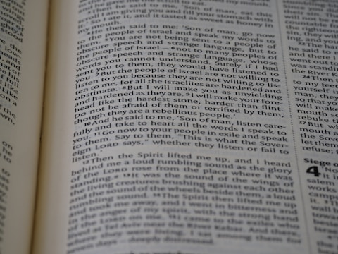 A close-up view of a page from a book, featuring text printed in a column layout. The text appears to be from a religious or philosophical work, with words and phrases presented in a structured format. The focus is on the middle of the page, with other text slightly blurred in the foreground and background.