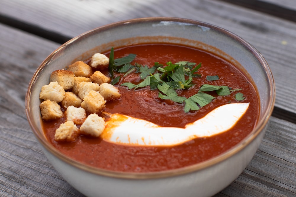 a bowl of tomato soup with croutons and parsley