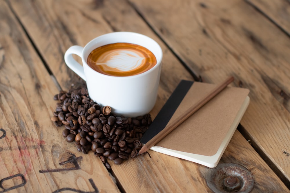 a cup of coffee sitting on top of a pile of coffee beans