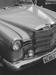 A classic car featuring a shiny chrome grill and headlight details, with smooth, curved lines and a distinct emblem on the hood.
