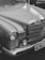 A classic car featuring a shiny chrome grill and headlight details, with smooth, curved lines and a distinct emblem on the hood.