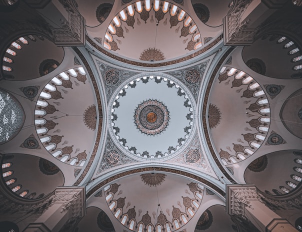A softly lit mosque interior with intricate geometric patterns glowing under golden lantern light.