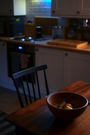A warm kitchen scene with fresh fruits and vegetables on a wooden table.