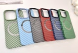 A collection of six carbon fiber-patterned phone cases, each with a circular magnetic ring design. The cases are arranged in a cascading order, showcasing a variety of colors including green, light blue, black, red, dark blue, and another shade of green.