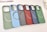 A collection of six carbon fiber-patterned phone cases, each with a circular magnetic ring design. The cases are arranged in a cascading order, showcasing a variety of colors including green, light blue, black, red, dark blue, and another shade of green.