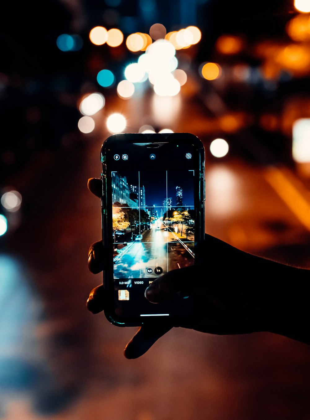 uma pessoa tirando uma foto de uma rua da cidade à noite