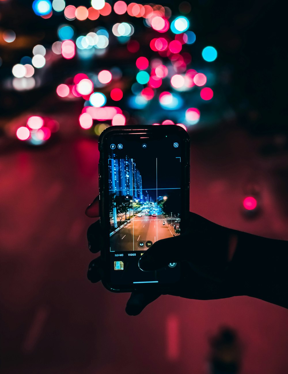 uma pessoa tirando uma foto de uma rua da cidade à noite