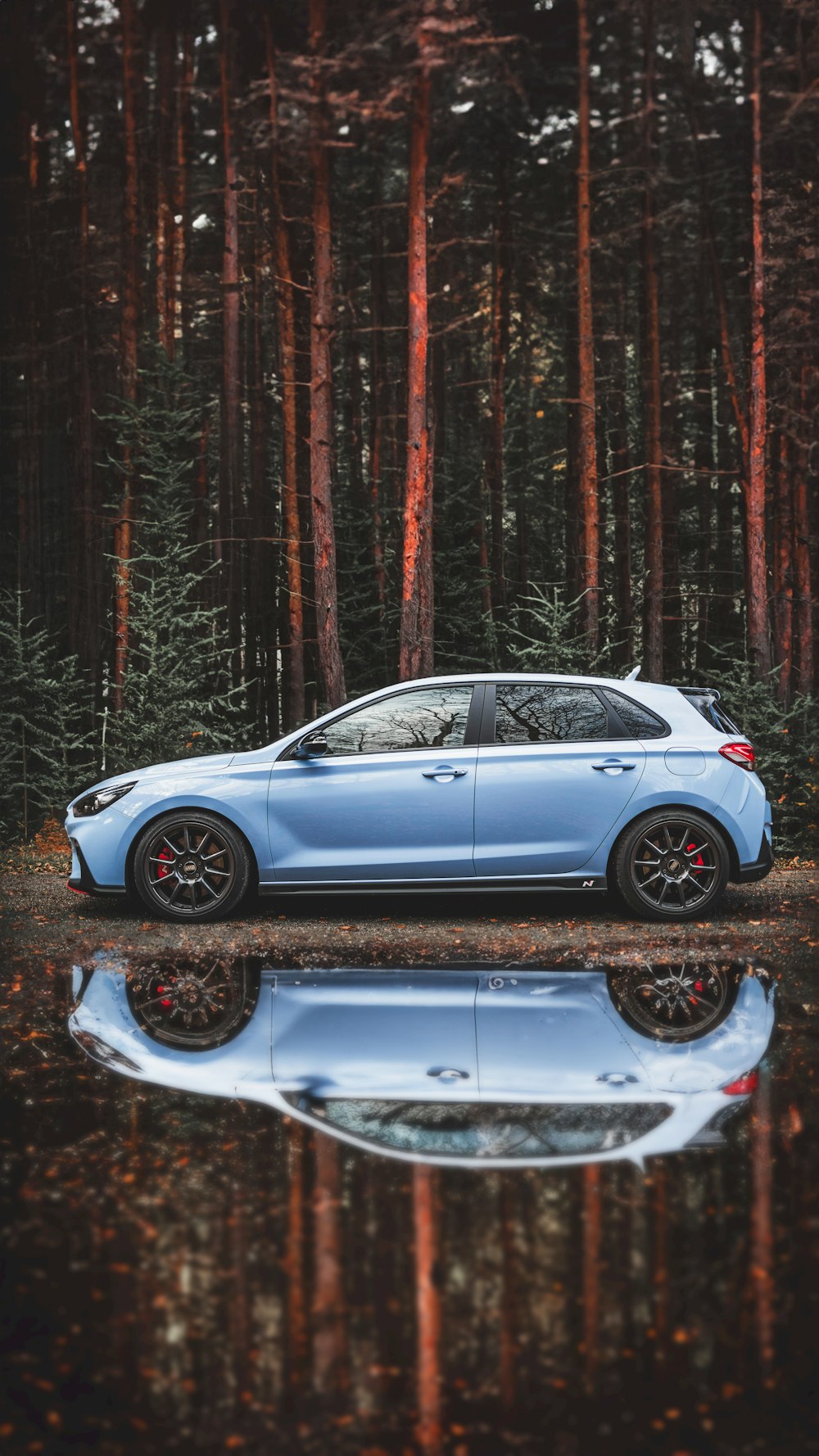 a blue car parked in front of a forest