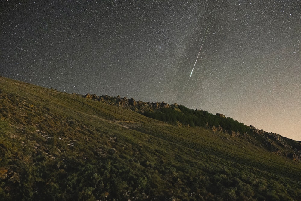 an airplane flying over a grassy hill under a night sky