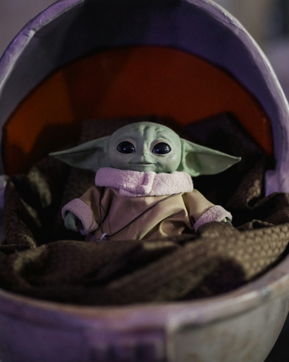 a baby yoda doll sitting inside of a purple container