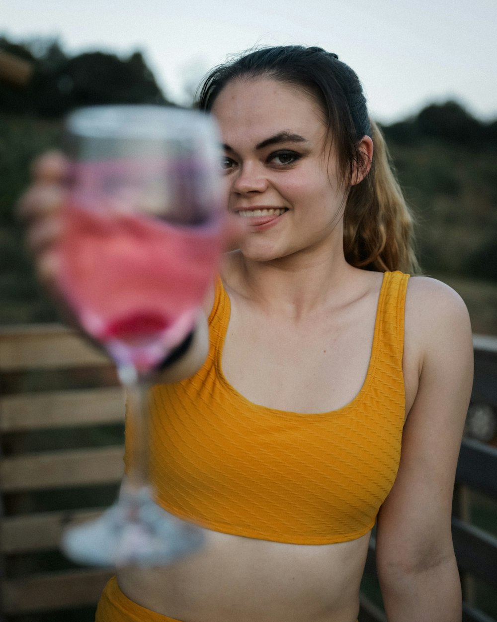 a woman in a yellow top holding a wine glass