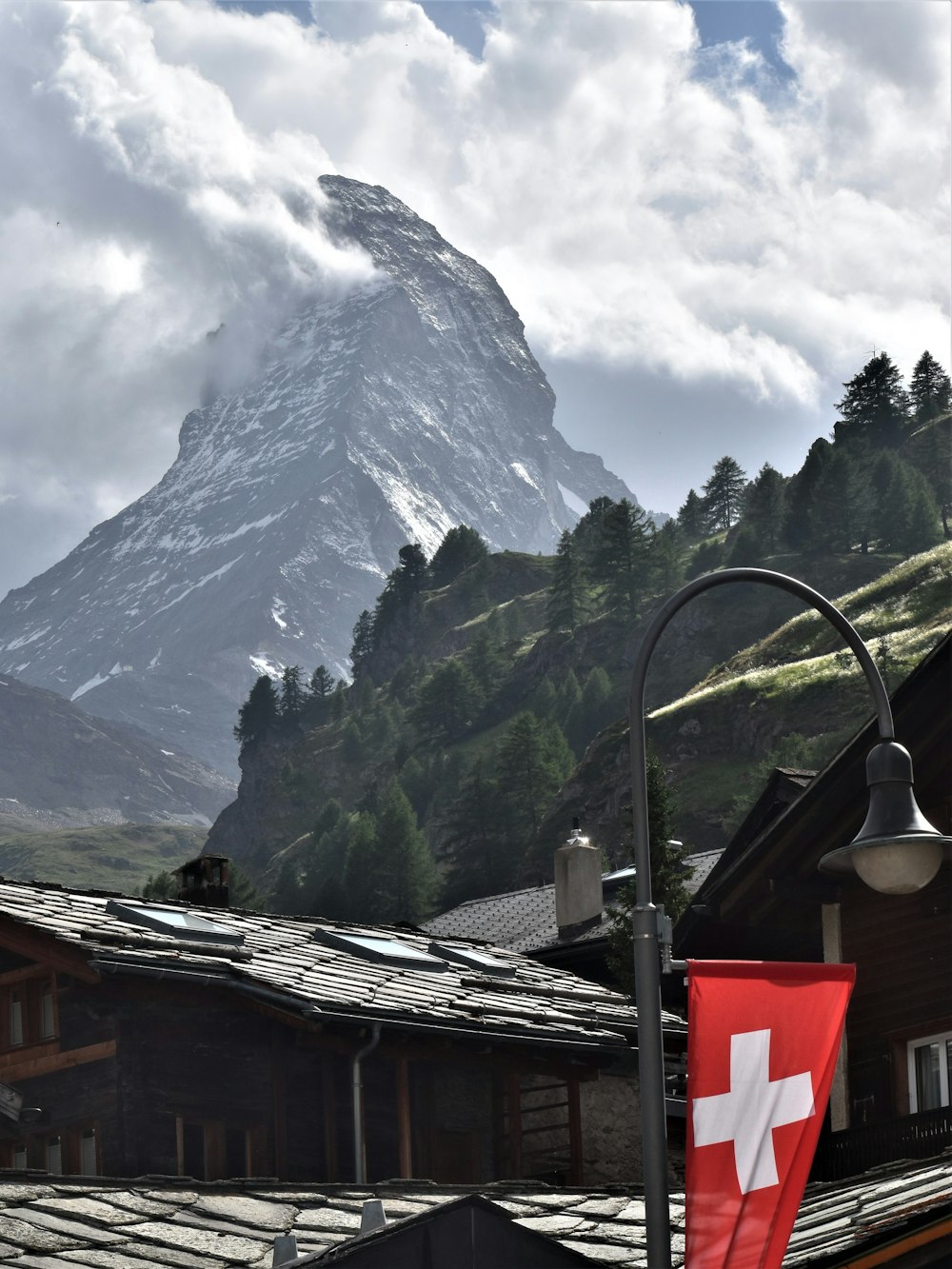 a swiss flag flying in front of a mountain