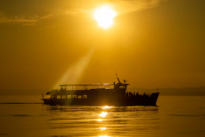 Golden sunset casting warm light over a sleek boat cutting through calm Gulf of Poets waters.