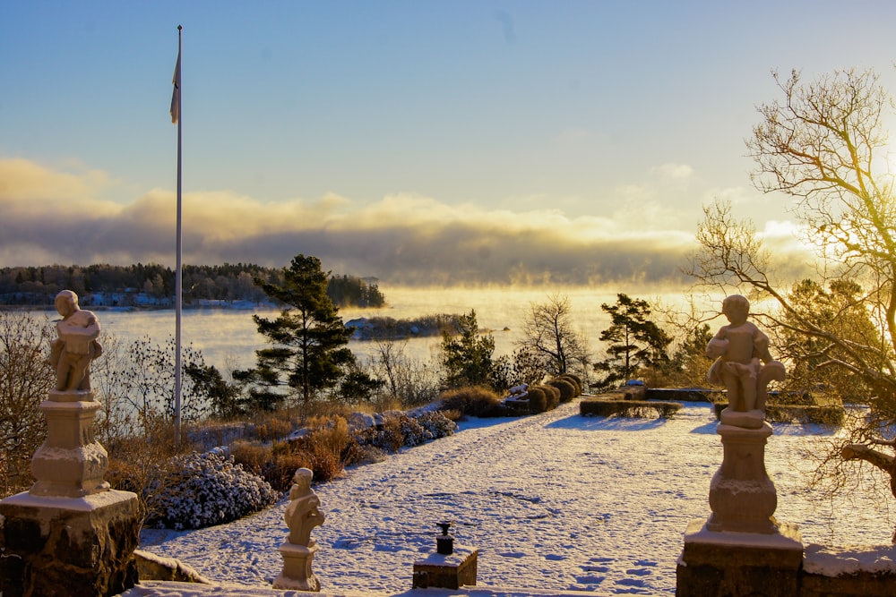 a snow covered walkway with statues and a flag pole