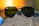 Close-up of sporty sunglasses resting on a rugged mountain trail at sunrise.