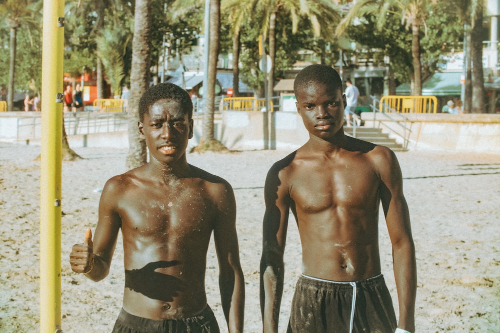 two young men standing next to each other on a beach