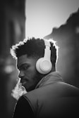The image features a man wearing large headphones and a vest. He is exhaling visible breath, suggesting a cold environment. The lighting creates a strong contrast, highlighting the headphones and his focused expression.