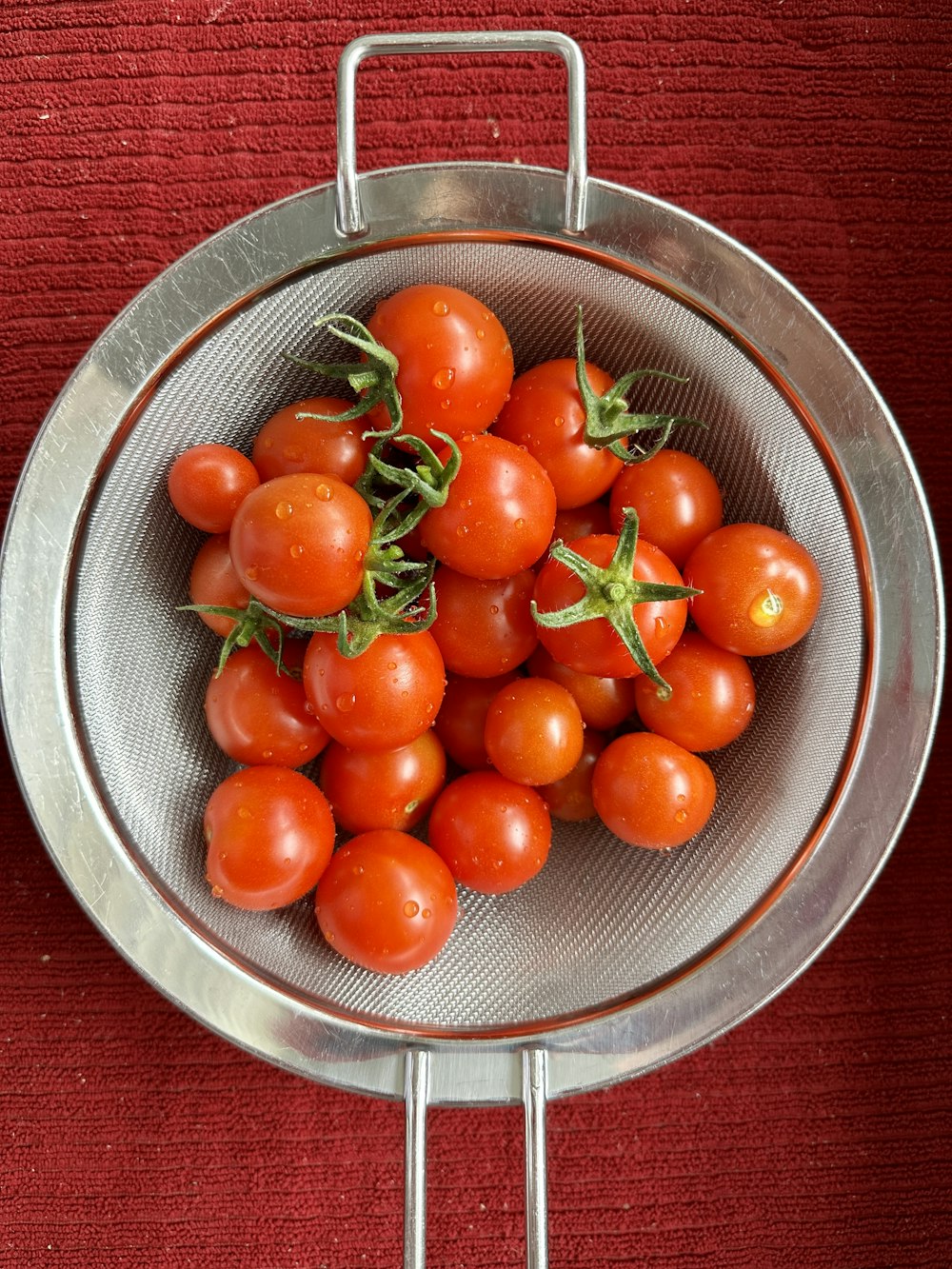 a metal bowl filled with lots of ripe tomatoes