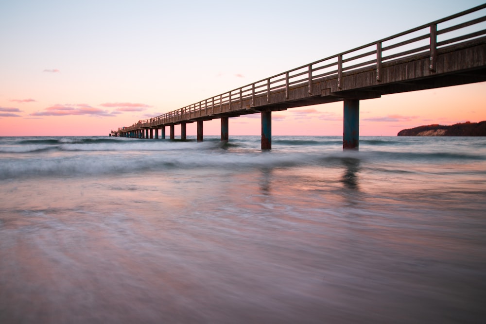 a long pier stretching into the ocean at sunset
