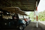a row of golf carts parked in a covered area